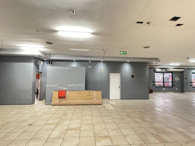 Spacious open-plan industrial area featuring tiled flooring, built-in service counter, and functional lighting, suitable for various commercial or retail applications.