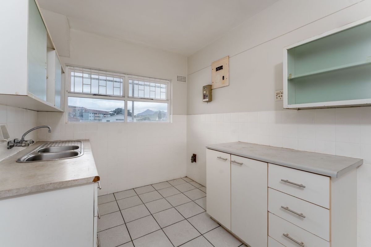 A functional, empty kitchen featuring tiled flooring, built-in cabinetry, laminate countertops, and a double bowl stainless steel sink with window views.