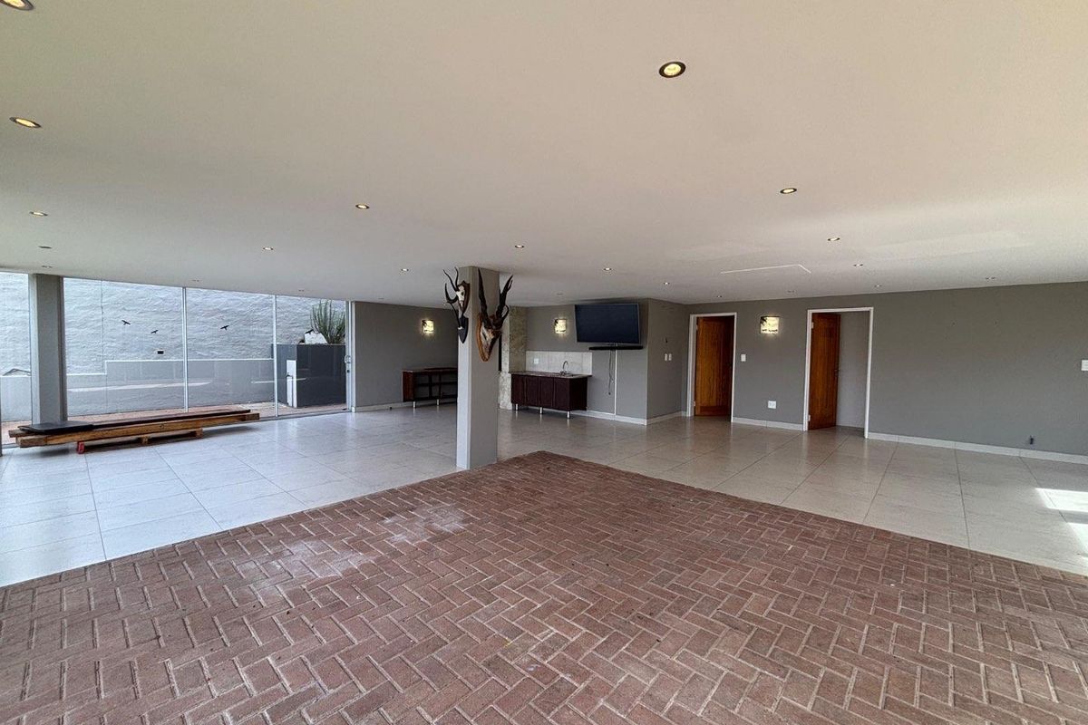 Spacious open-plan living area featuring a mix of brick and tile flooring, built-in bar cabinetry, and large sliding glass doors leading to the exterior.