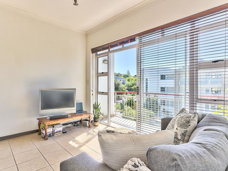 Bright living room featuring tiled flooring and large sliding glass doors that provide direct access to a private balcony.