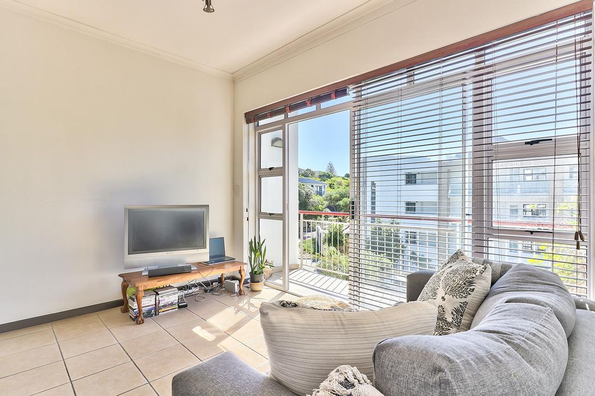 Bright living room featuring tiled flooring and large sliding glass doors that provide direct access to a private balcony.
