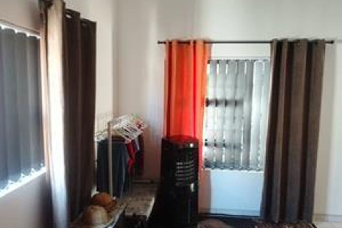 A bedroom interior featuring vertical blinds on windows and curtain rods, providing basic natural light control and privacy.