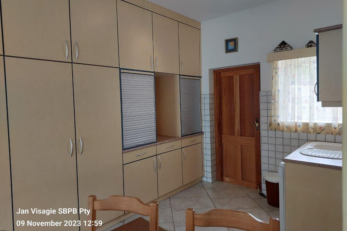 A functional kitchen area featuring extensive built-in cabinetry, laminate countertops, a single basin sink, and tiled flooring.