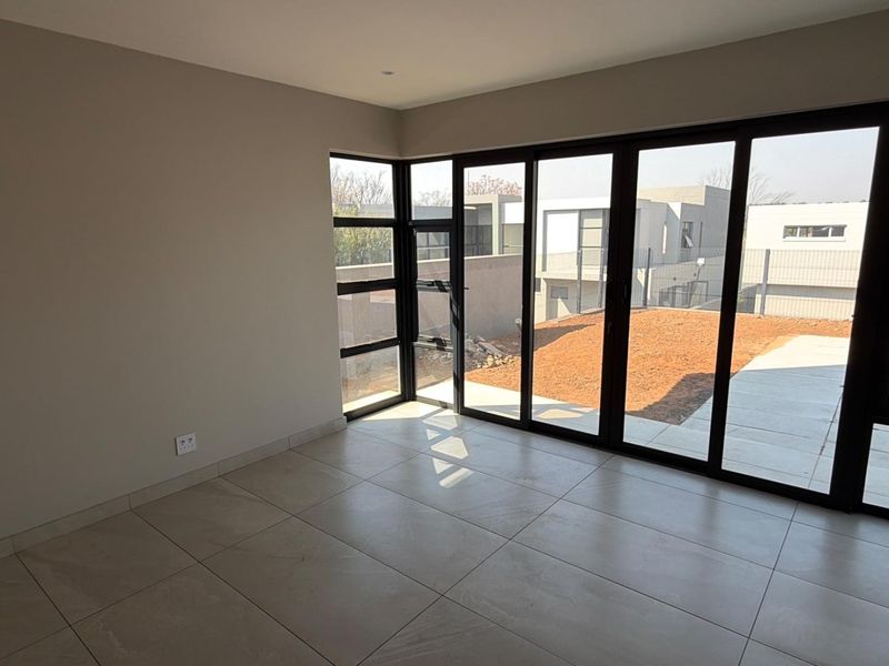 Bright and modern living area featuring large format floor tiles and expansive black aluminium sliding doors opening to the rear garden.
