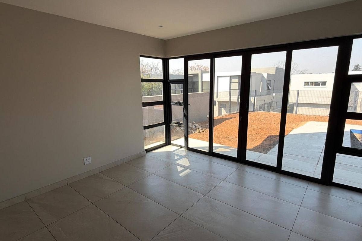 Bright and modern living area featuring large format floor tiles and expansive black aluminium sliding doors opening to the rear garden.
