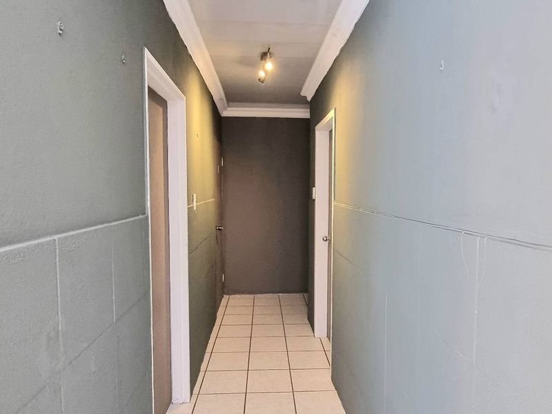 A functional hallway featuring tiled flooring and neutral wall finishes, providing access to multiple rooms within the home.
