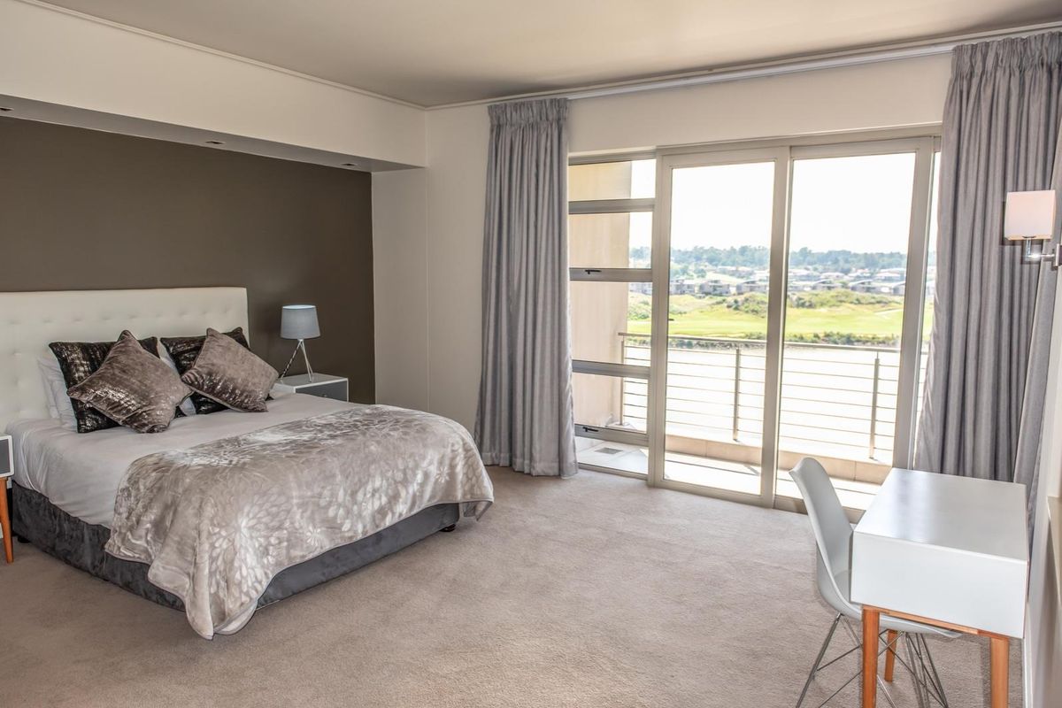 Spacious bedroom featuring neutral carpeting, a feature wall, and large sliding glass doors opening onto a private balcony with scenic views.