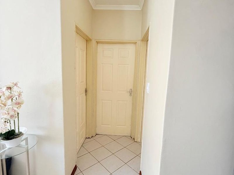 A clean and well-maintained hallway featuring tiled flooring, coved ceilings, and multiple panelled interior doors providing access to adjacent rooms.