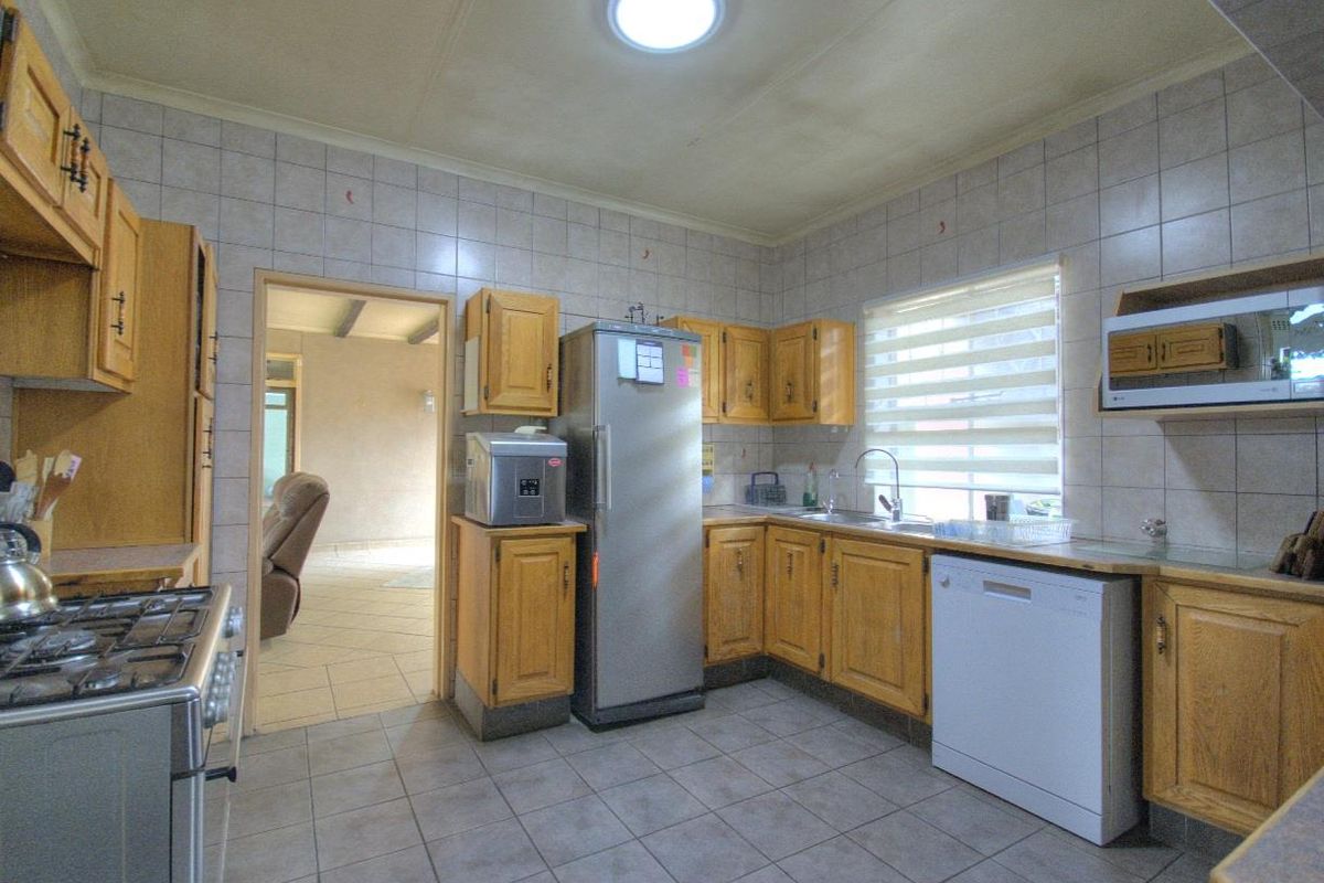 Functional kitchen featuring wooden cabinetry, tiled walls, built-in stove, and integrated sink area with ample counter space.
