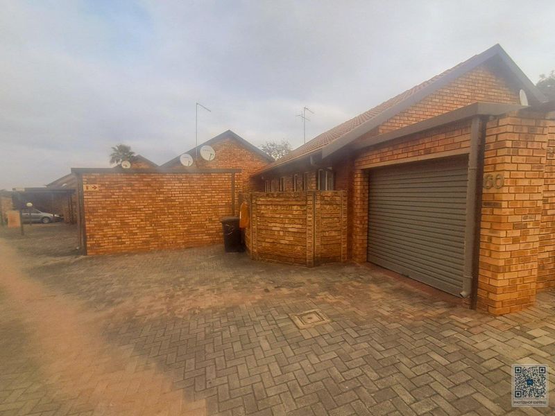 Front exterior view of a townhouse featuring a brick facade, a single roller garage door, and a paved driveway.