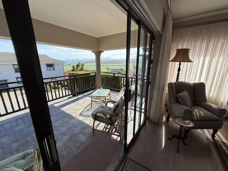 A covered balcony featuring tiled flooring and a railing, offering expansive views and seamless indoor-outdoor flow through large sliding glass doors.