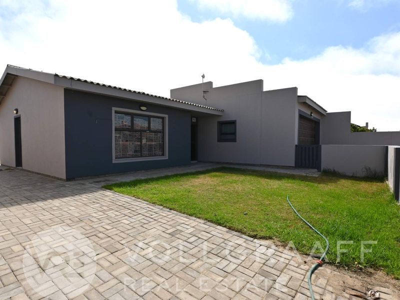 Front exterior view of the house featuring a paved driveway, small lawn area, and modern facade with a garage.