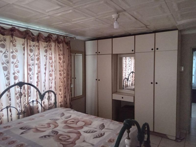 A bedroom featuring a large built-in wardrobe with an integrated vanity mirror and a tiled ceiling finish.