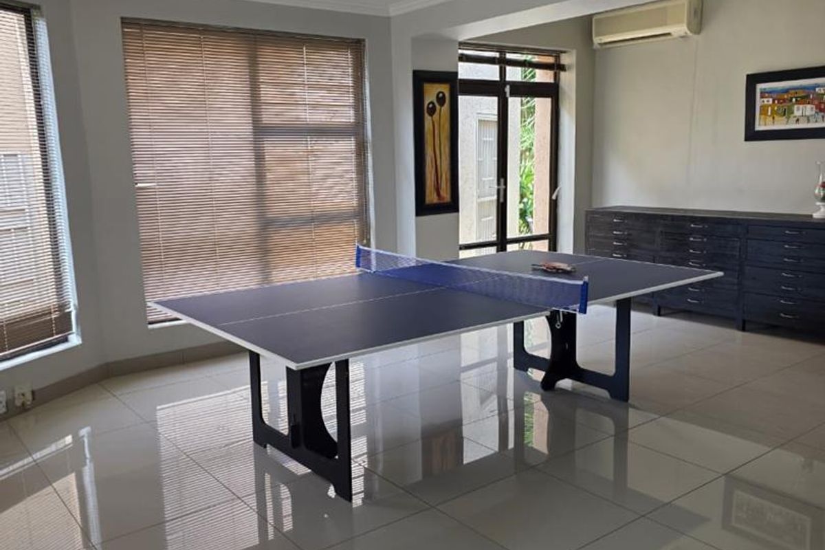 Spacious living area featuring large format floor tiles, recessed lighting, and split-system air conditioning, with direct access to outdoor space via french doors.