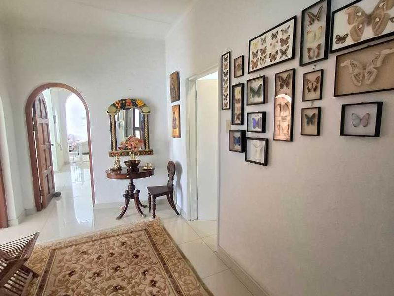 A bright, tiled hallway featuring an arched doorway leading to an adjacent room and a gallery wall.