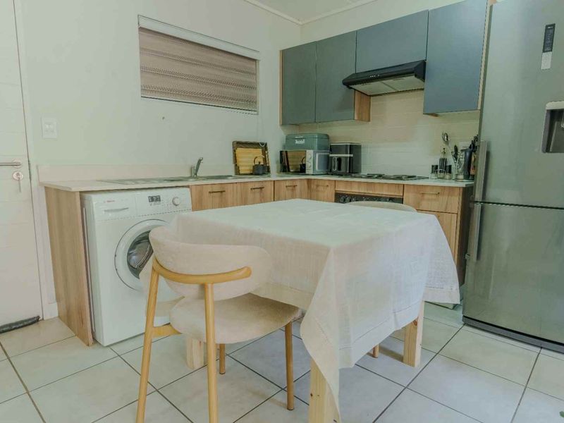 A functional kitchen featuring built-in cabinetry, laminate countertops, a stainless steel sink, and an integrated extractor fan with tiled flooring.