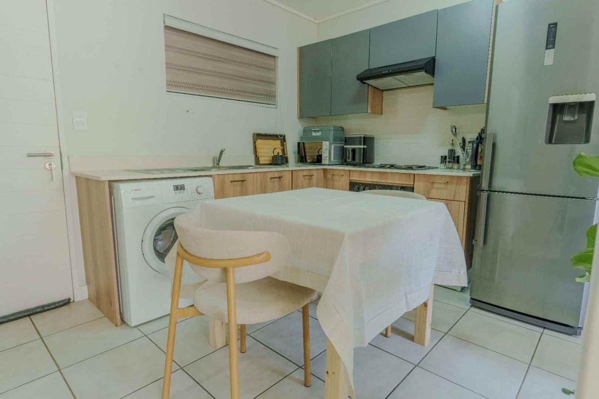 A functional kitchen featuring built-in cabinetry, laminate countertops, a stainless steel sink, and an integrated extractor fan with tiled flooring.