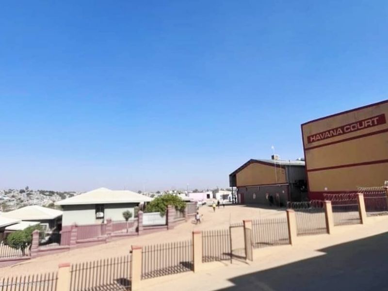 Exterior view of the Havana Court apartment complex featuring a paved driveway and perimeter fencing.
