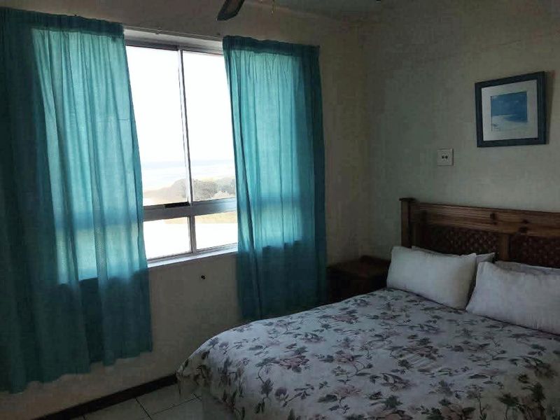 A bedroom featuring tiled flooring, a ceiling fan, and a sliding window with views.
