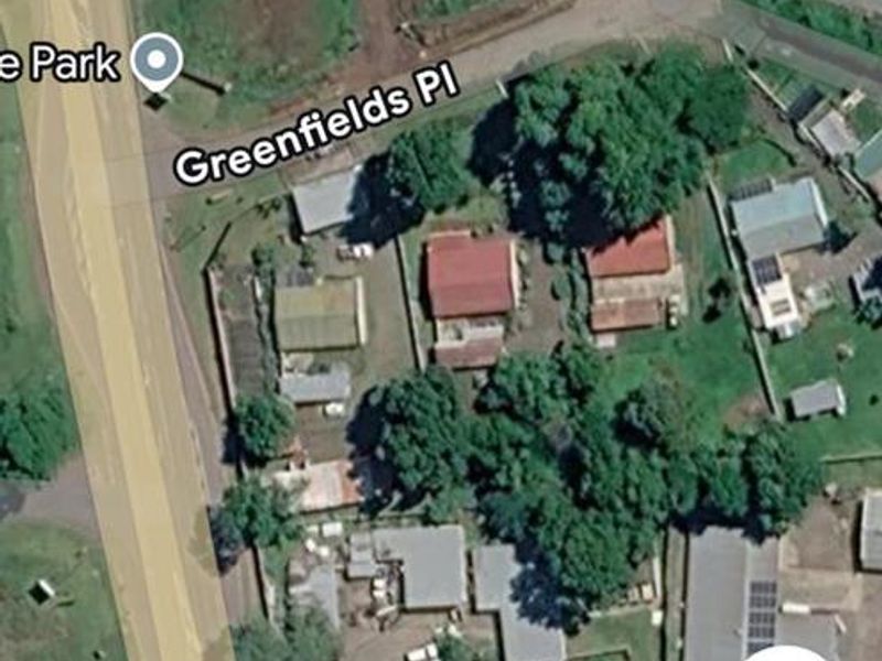 An aerial satellite view of the property and surrounding neighborhood, showing the site layout and access from the main road.