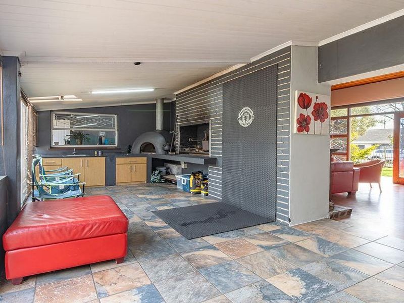Covered patio area featuring a built-in braai, pizza oven, and functional kitchenette cabinetry, providing an ideal space for outdoor entertaining.