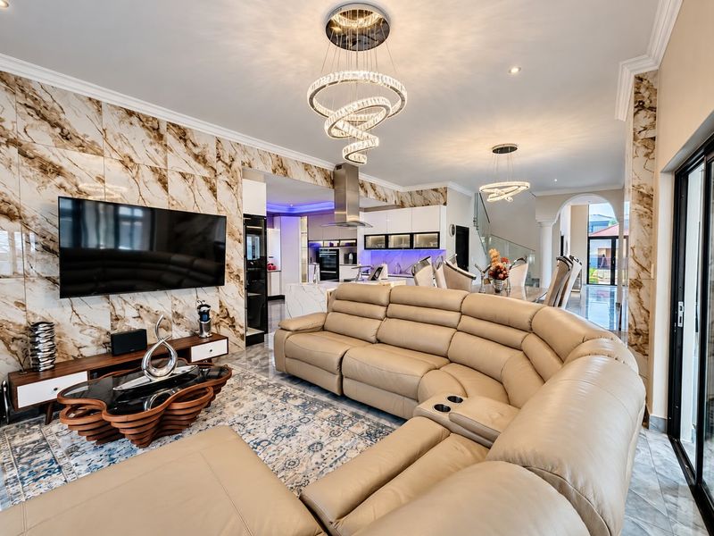 A luxurious open-plan living and kitchen area featuring marble-effect wall cladding, modern crystal chandeliers, and high-end finishes throughout.