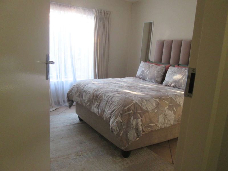 A bedroom featuring tiled flooring and a window with curtain tracks, viewed from the doorway.