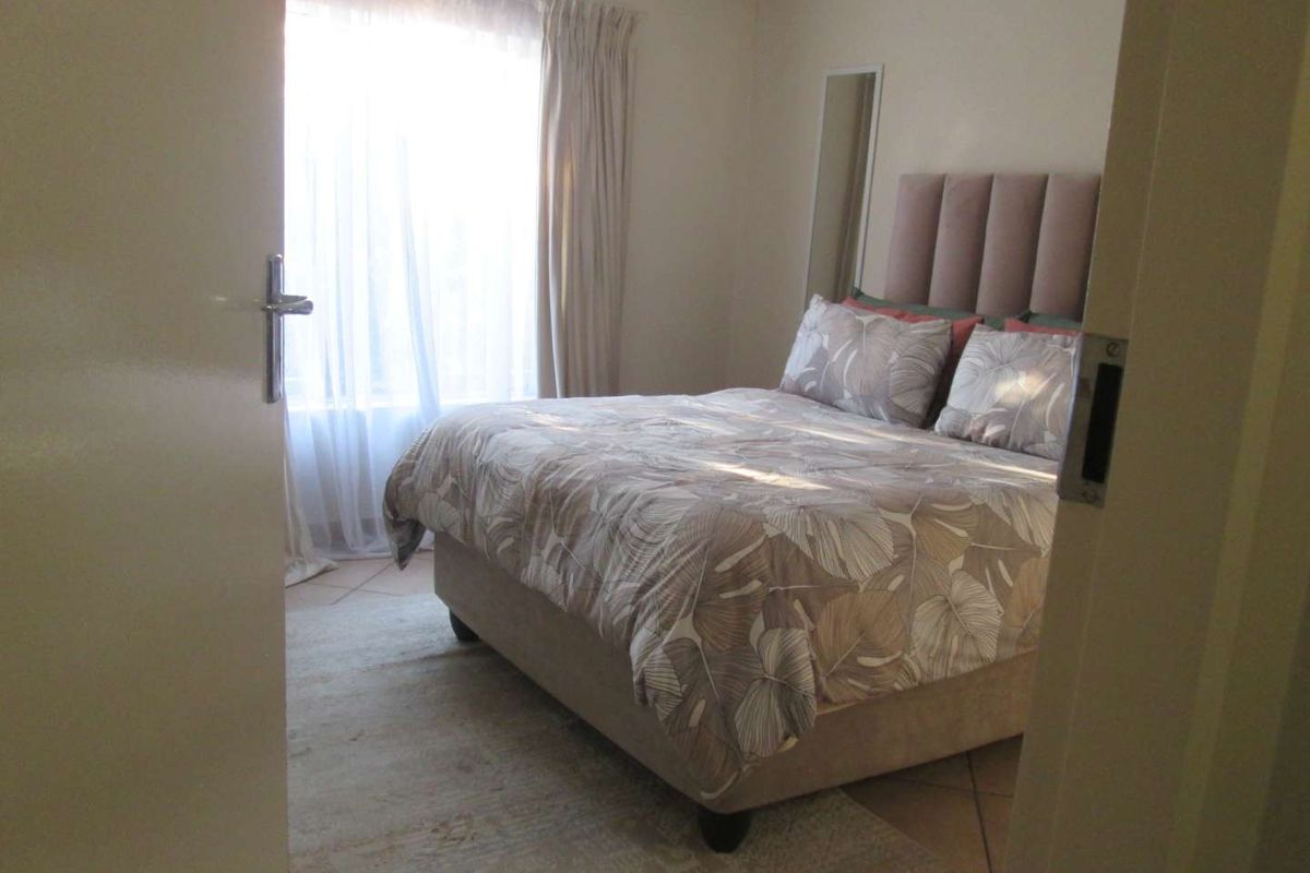 A bedroom featuring tiled flooring and a window with curtain tracks, viewed from the doorway.