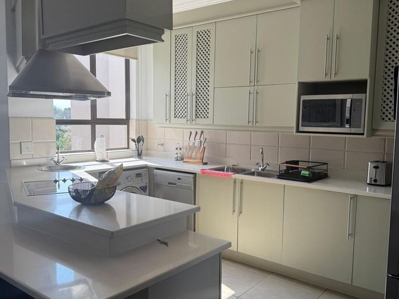 Modern kitchen featuring light-toned cabinetry, stone countertops, integrated appliances, and a functional breakfast nook with ample natural light.