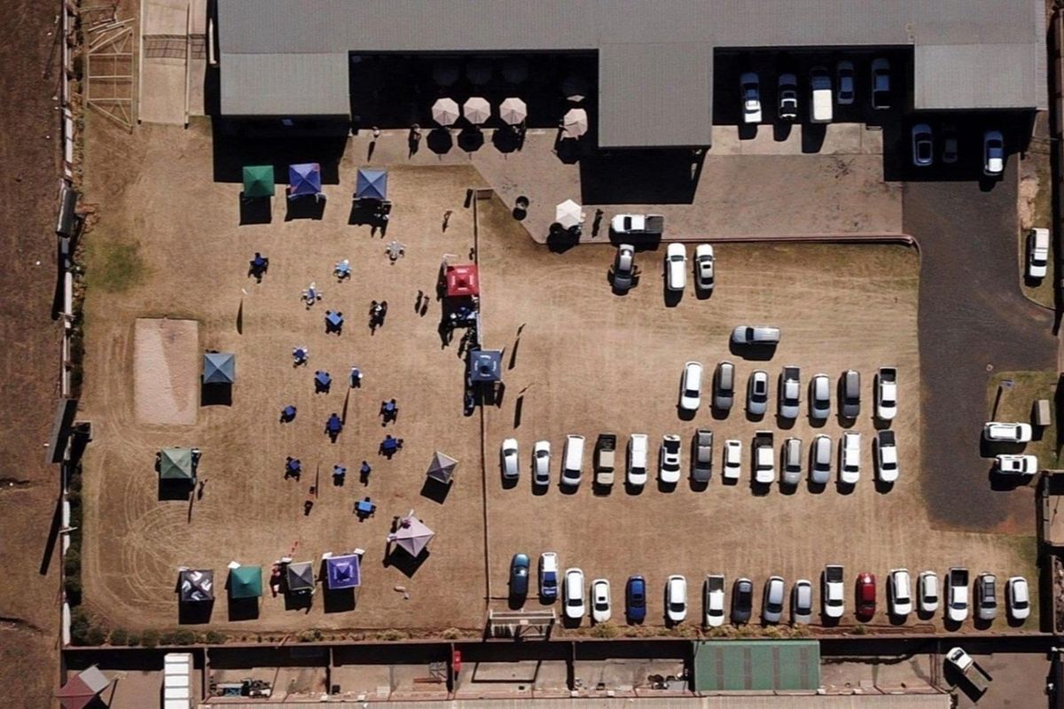 Aerial view of a commercial property featuring a large parking lot and an open outdoor area with various temporary structures.