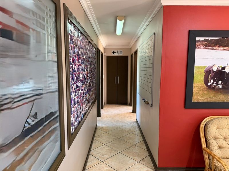 A functional hallway featuring tiled flooring, crown molding, and access to multiple rooms via double doors.