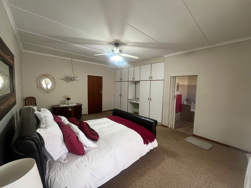 Spacious bedroom featuring built-in cupboards, a ceiling fan, and direct access to an en-suite bathroom.