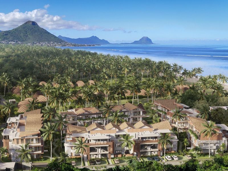 An aerial view of a luxury coastal residential development featuring modern architecture, lush tropical landscaping, and proximity to the beach and mountains.