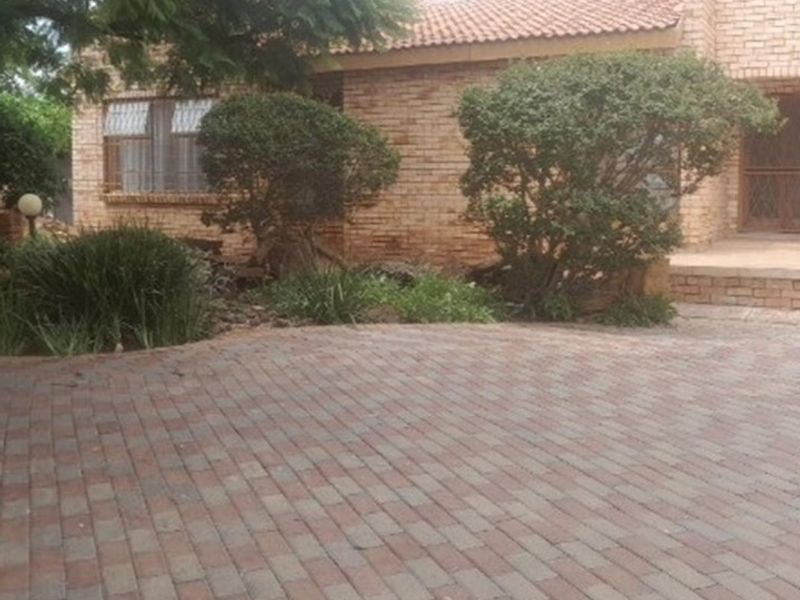 Front view of a face brick house featuring a paved driveway and established garden landscaping.