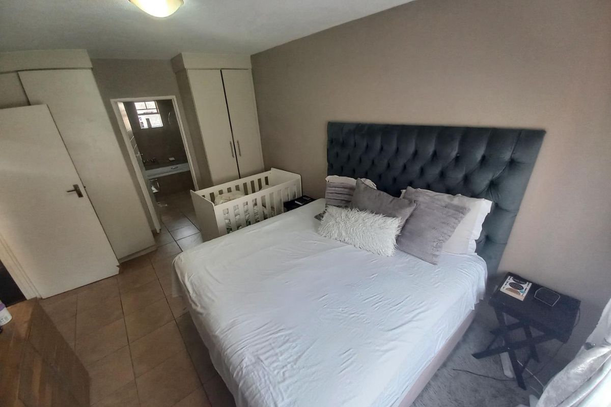 A bedroom featuring built-in cupboards and an en-suite bathroom, finished with tiled flooring.