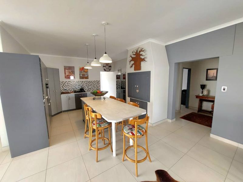 Open-plan kitchen featuring a central island with breakfast bar seating, tiled flooring, and modern cabinetry with integrated appliances.