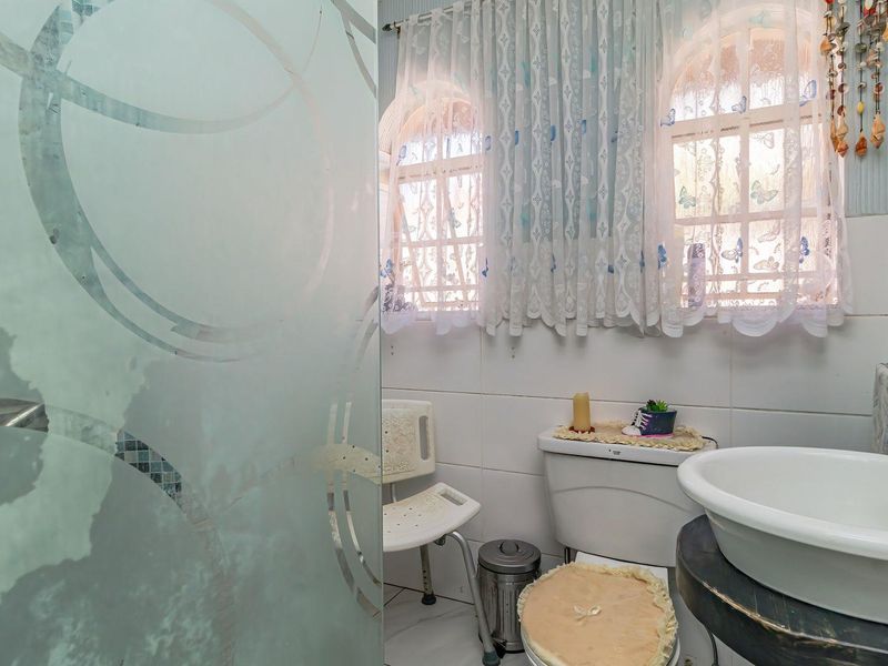 A functional bathroom featuring a vessel sink, toilet, and a frosted glass shower screen with tiled finishes.