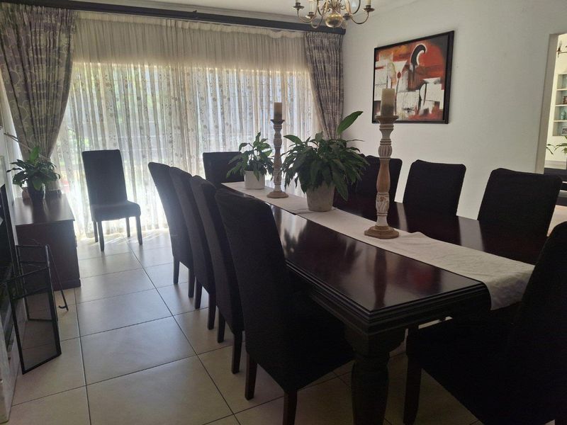 A formal dining room featuring large format floor tiles and a sliding glass door providing access to the exterior.