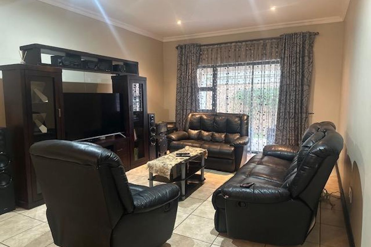 A comfortable living room featuring tiled flooring, recessed ceiling lighting, and large sliding glass doors providing access to the outdoor area.