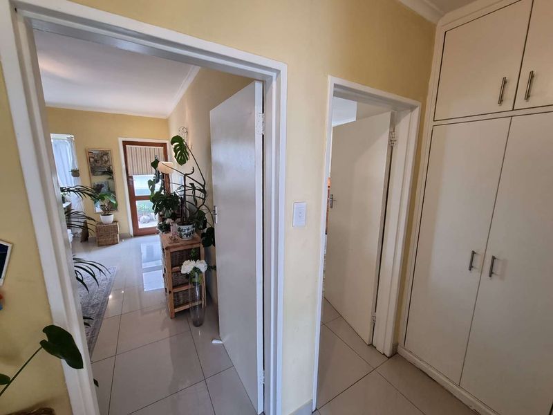 A functional hallway featuring tiled flooring and built-in storage cupboards, providing access to adjacent living areas and rooms.