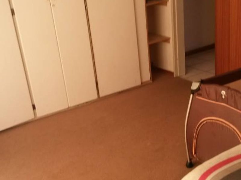 Bedroom featuring built-in cupboards and integrated shelving, with carpeted flooring and access to an adjoining hallway.
