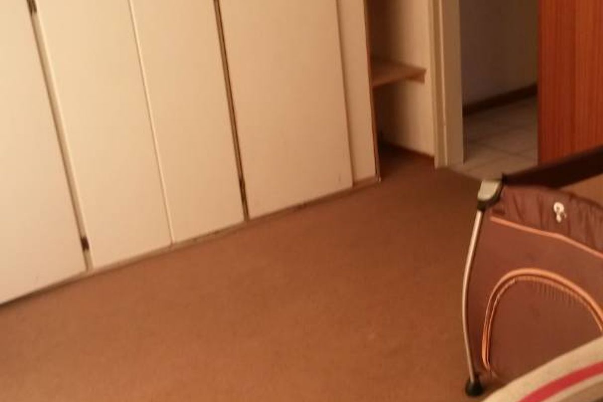 Bedroom featuring built-in cupboards and integrated shelving, with carpeted flooring and access to an adjoining hallway.