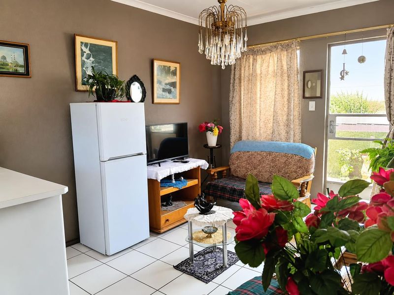A living area featuring tiled flooring, a glass panel door leading to the exterior, and a decorative chandelier.