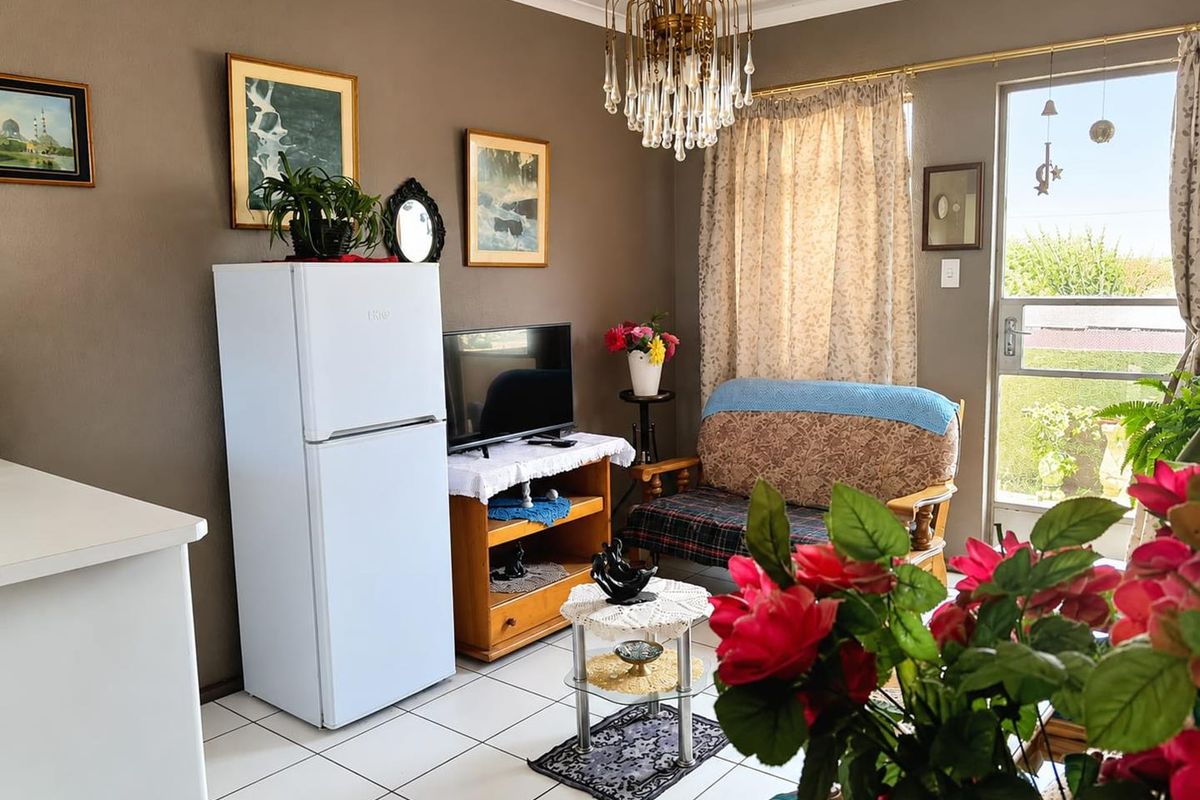 A living area featuring tiled flooring, a glass panel door leading to the exterior, and a decorative chandelier.