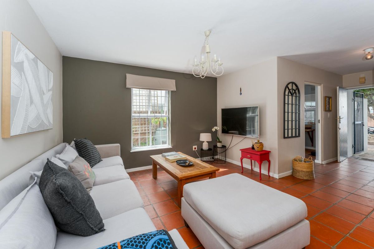 A cozy living room featuring terracotta floor tiles, a feature wall, and direct access to the exterior entrance.