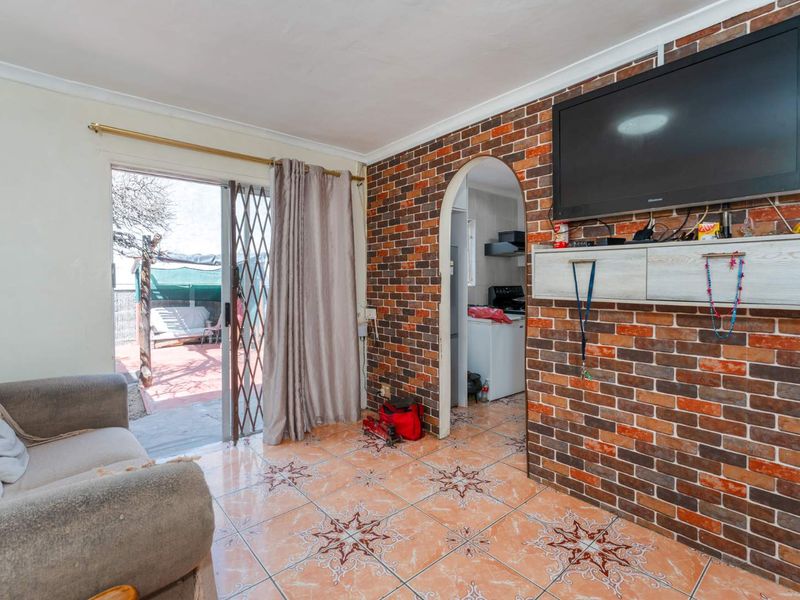 Living room featuring an exposed brick wall, tiled flooring, and a sliding door providing access to the outdoor patio area.
