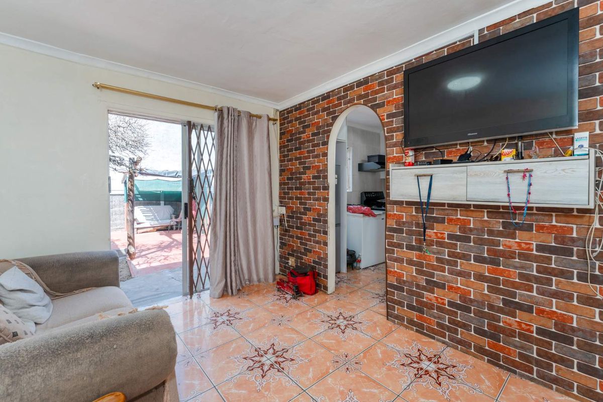 Living room featuring an exposed brick wall, tiled flooring, and a sliding door providing access to the outdoor patio area.