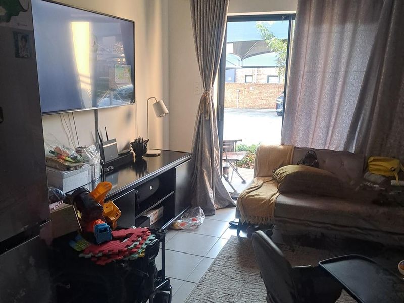 A living room area featuring tiled flooring and a sliding glass door providing access to the exterior.
