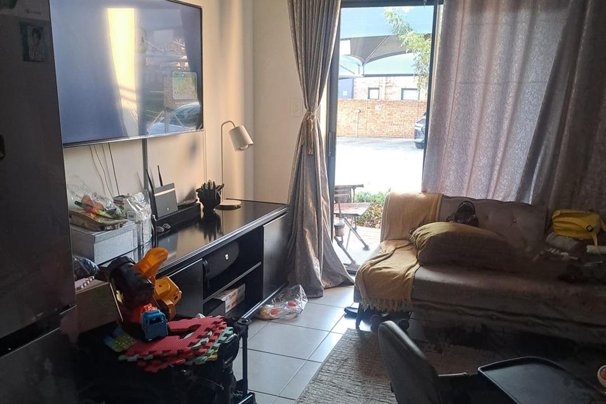 A living room area featuring tiled flooring and a sliding glass door providing access to the exterior.