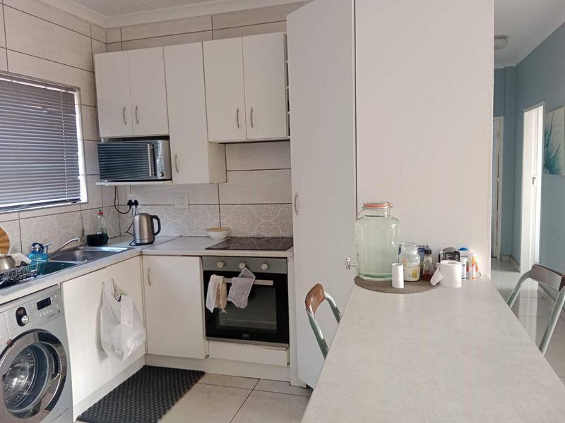 A functional kitchen featuring white cabinetry, built-in oven and hob, tiled backsplash, and an integrated breakfast counter for casual dining.